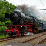 Vintage steam train passing through lush greenery in Baarn, Utrecht, Netherlands.